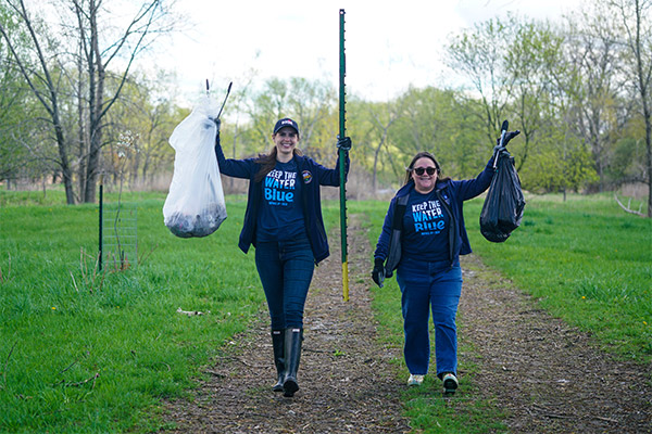 Two employees holding up full trash bags